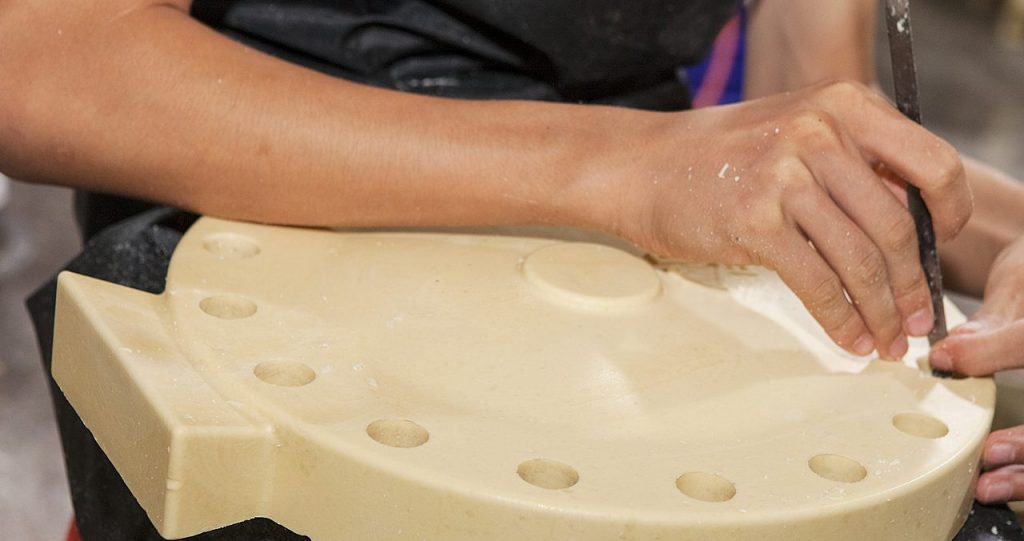 Lost-wax casting. Manual worker is cleaning the wax model before covered by sand ceramic.