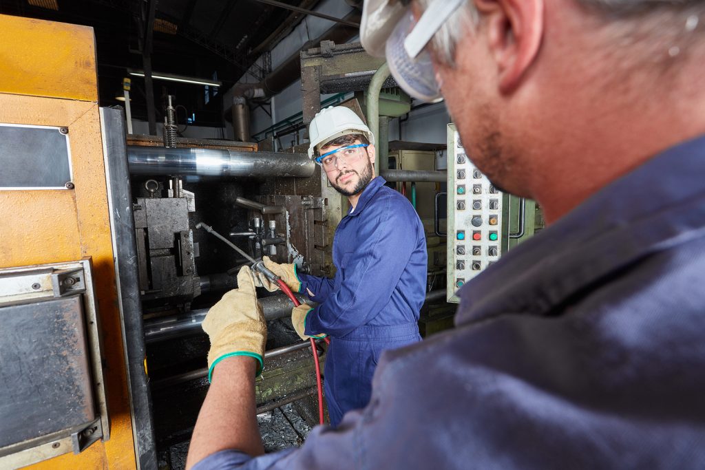 Foundry workers manufacturing metal workpieces in metallurgy fac